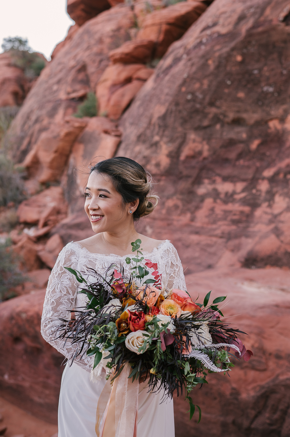 The beautiful bride in her all white wedding dress with lace detailing on the top. Holding her wedding bouquet mixed with flowers, greenery and lavender in Ash Springs.