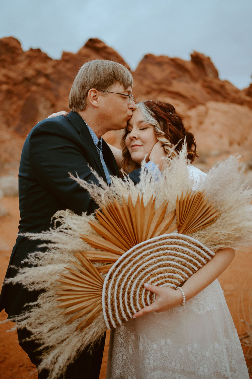 Groom kissing forehead of Bride holding pampas grass bouquet for boho chic elopement 