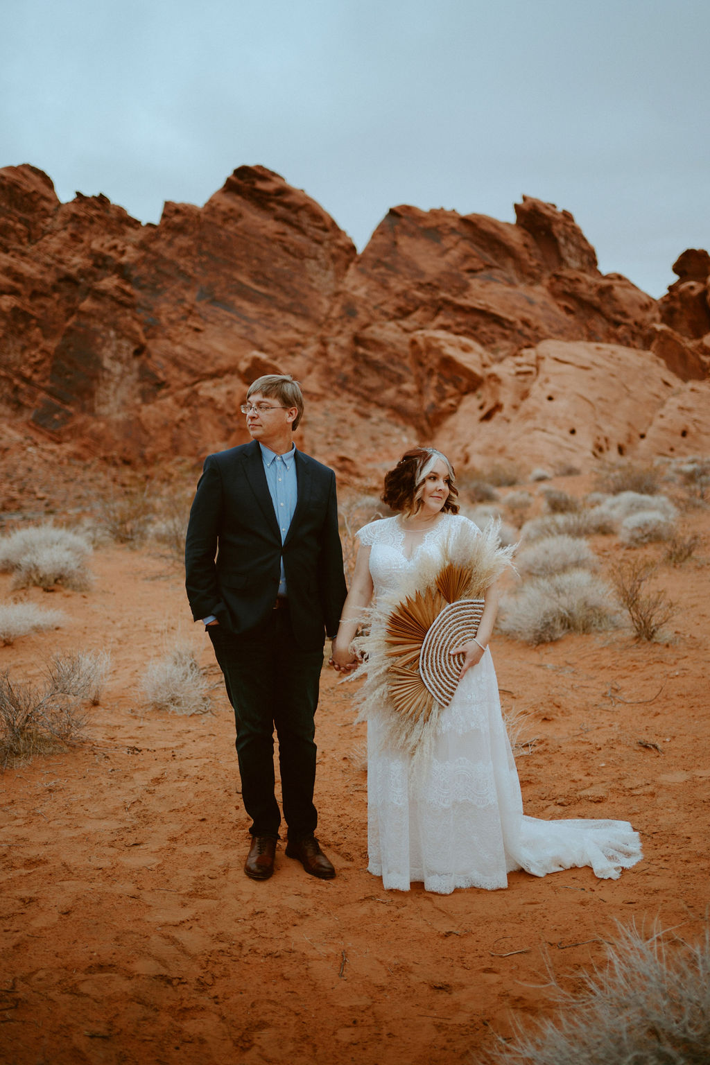 Newlyweds holding hands in red rock desert 