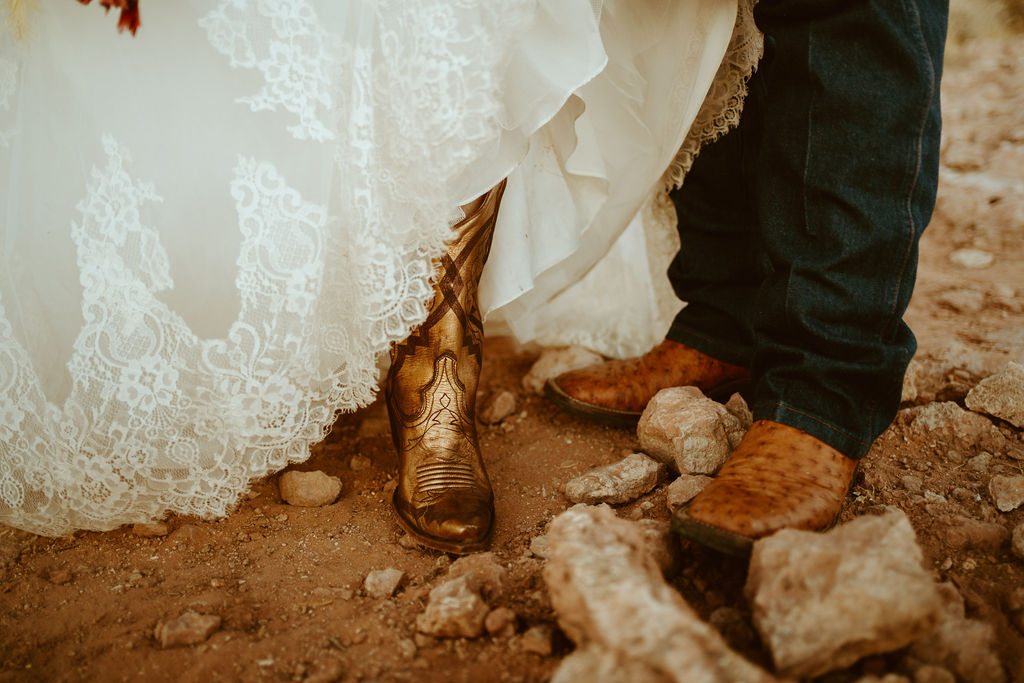 Bride wearing Metallic Boots and detailed lace dress and Groom in Cowboy boots for desert elopement 