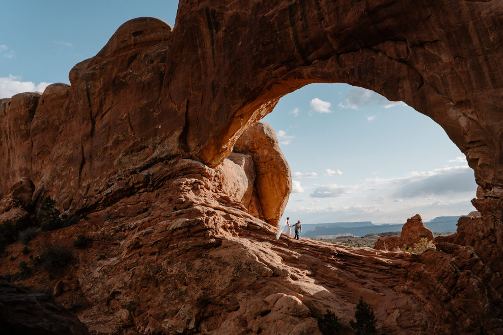 How To Start Planning a Destination Wedding. Couple in the middle of an arch with breathtaking views in Moab, Utah.
