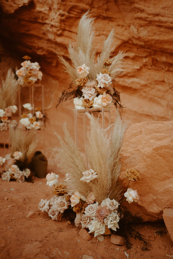 Las Vegas has the Craziest Winds! Ground floral arch placed for elopement at in the red rock. The floral arches have beautiful pampas mixed in with pinks, creams, and toffee colored flowers. 