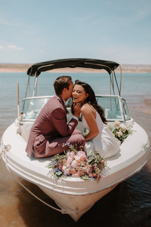 Newlywed wedding couple on ski boat at lake powell arizona, couple kissing on the front of a boat, groom in mauve tux / suit 