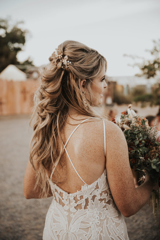 What is a boho styled wedding. Boho bridal hair half up hair do with a fishtail braid and soft waves with hair clips on each side. 
