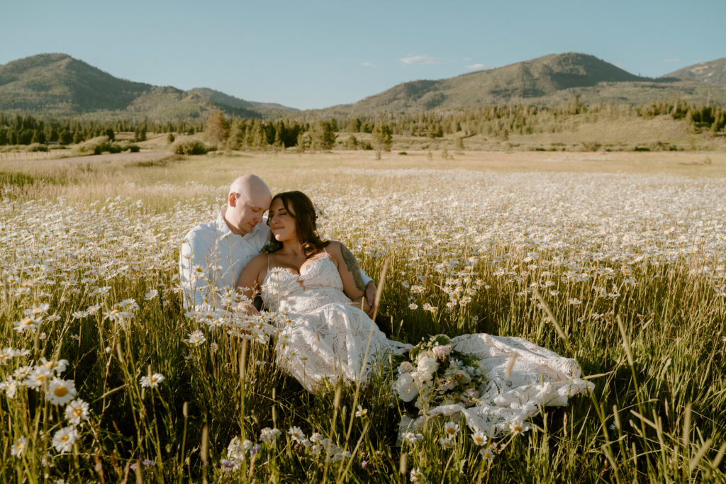 What is a Rustic & Whimsical Styled Wedding? Newlyweds laying in a bed of daisy's with the brides
