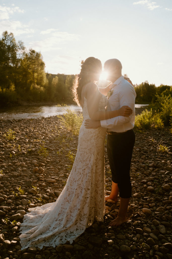 Newlyweds kissing by the lake with the sun setting behind them at steamboat in colorado.