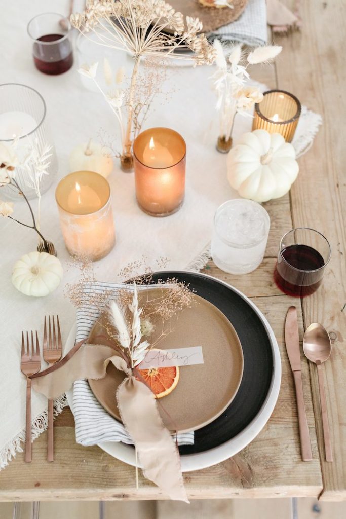 How to style the perfect thanksgiving table! Simple and minimal thanksgiving table scape. Dried fruit, bunny tails and a neutral ribbon with a vellum hand written name card for a pop of color and personalization. Tiny pumpkins and amber votives placed around the table. 