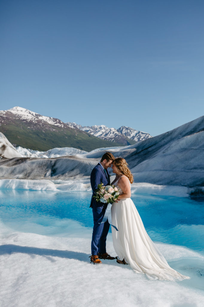 How to decide if you want an elopement or traditional wedding. Newlyweds standing in the middle of a glacier in Alaska for ceremony.