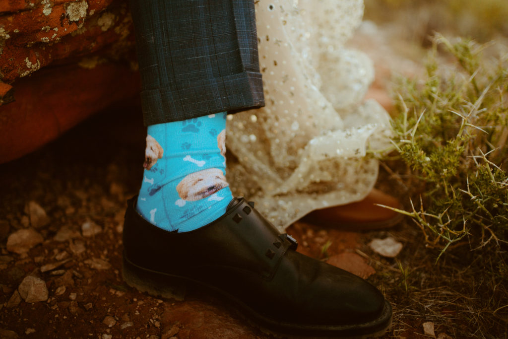 How To Include Your Dog on Your Wedding Day! Groom wearing custom socks of his dogs face with bones and paw prints. 