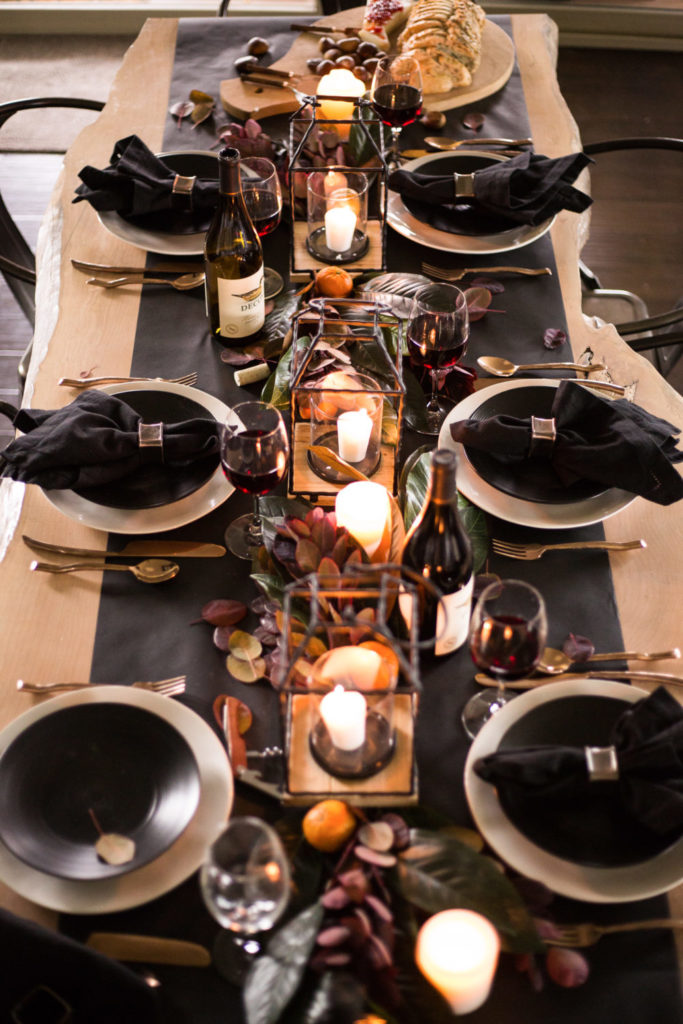 How to style the perfect thanksgiving table! Modern and moody thanksgiving table scape. Black butcher paper with purple foliage and magnolias with modern wooden black lanterns with lit candles. 
