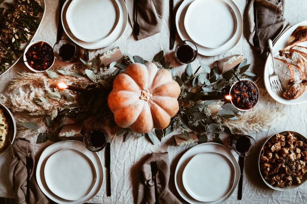 How to style the perfect thanksgiving table! Beautiful rustic family style thanksgiving table scape. With greenery, pampas grass, candles and a pumpkin as the center piece. 