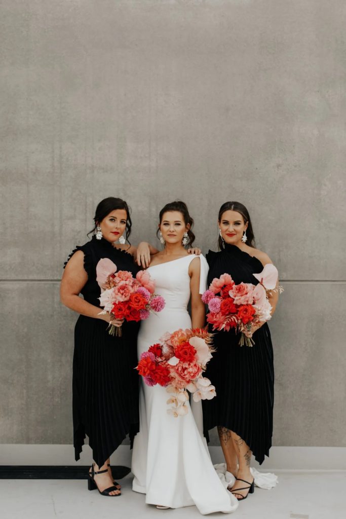 The Official List of 2023 Wedding Trends! Bride and brides maid holding their bright and bold bouquets 