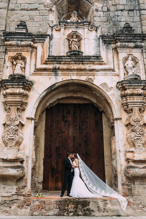 Top 10 Destination Wedding Locations for 2023! Couple kiss in front of the beautiful historic church in Guatemala