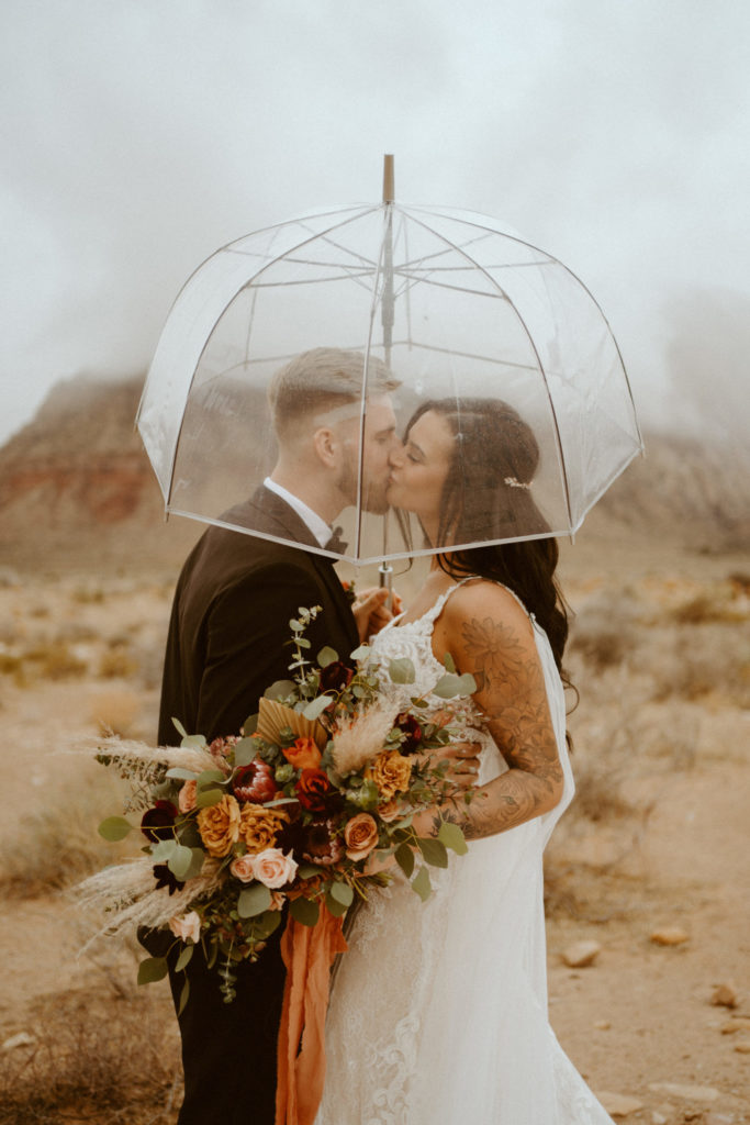 Newlyweds under transparent umbrella during cloudy day 