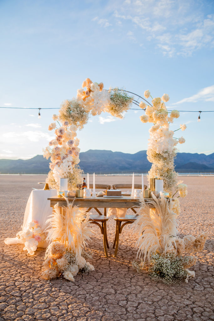 How to decide if you want an elopement or traditional wedding. Beautiful modern romantic sweetheart table in front of a floral covered arch for the background in the dry lake beds