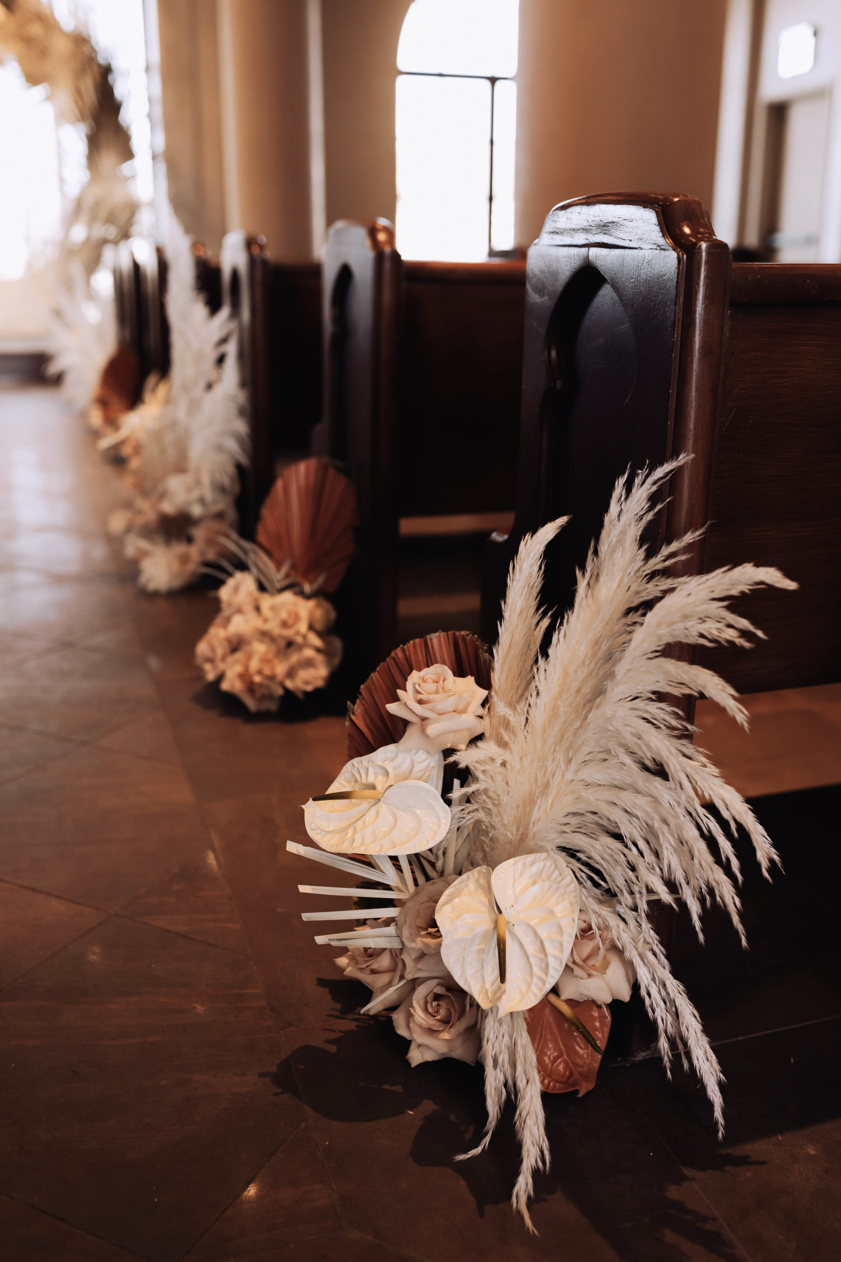 Lake Las Vegas Meets Modern Boho Bride. Florals mixed in with pampas grass. palm leaf's and orchids placed down the aisle at every pilar 