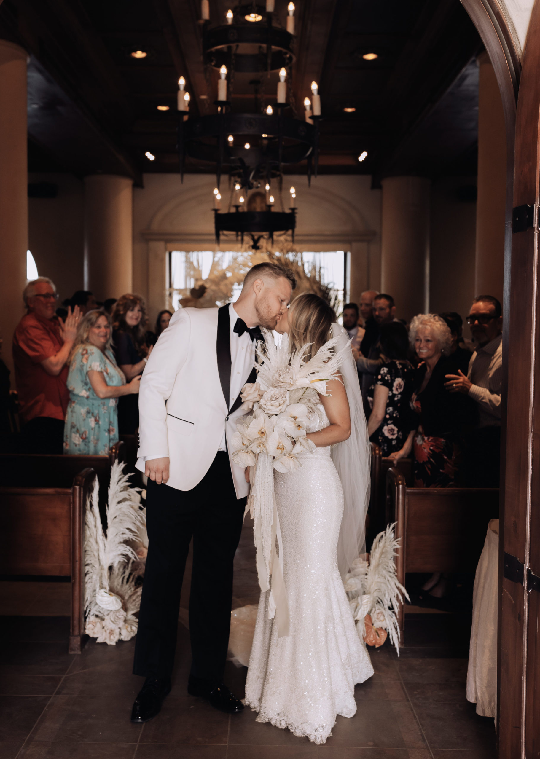 Lake Las Vegas Meets Modern Boho Bride. Newlyweds kiss at the end of the aisle in the doorway of the chapel
