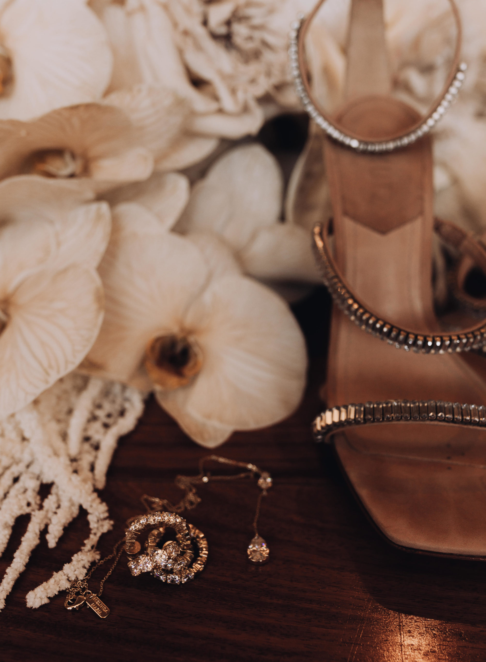 Lake Las Vegas Meets Modern Boho Bride. Detail of the brides accessories with her wedding day shoes, diamond earrings and necklace with pieces of her bouqet