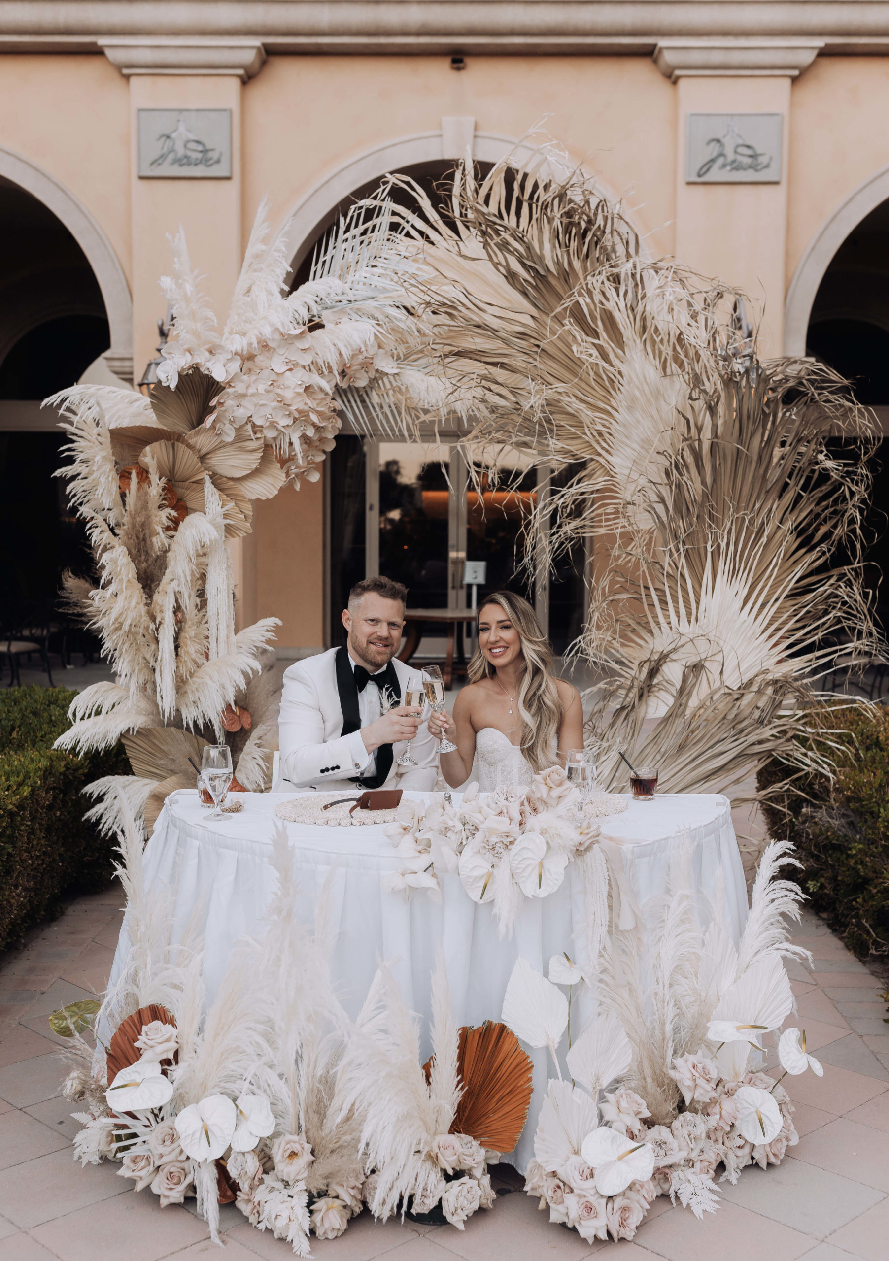 Lake Las Vegas Meets Modern Boho Bride. Beautiful boho couple cheers with champagne at the sweetheart table 