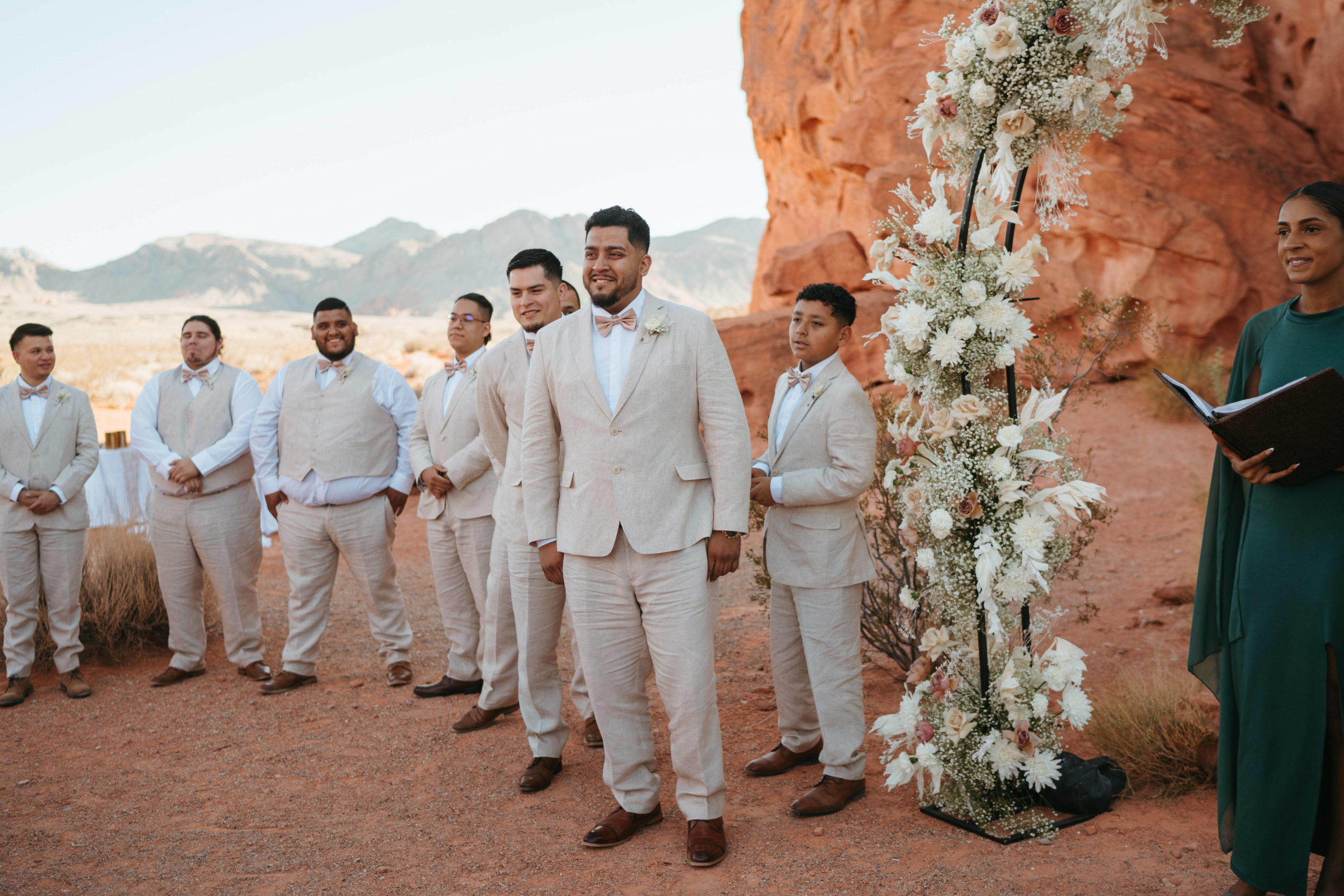 The groom and grooms men at the altar waiting for the bride to walk down the desert aisle