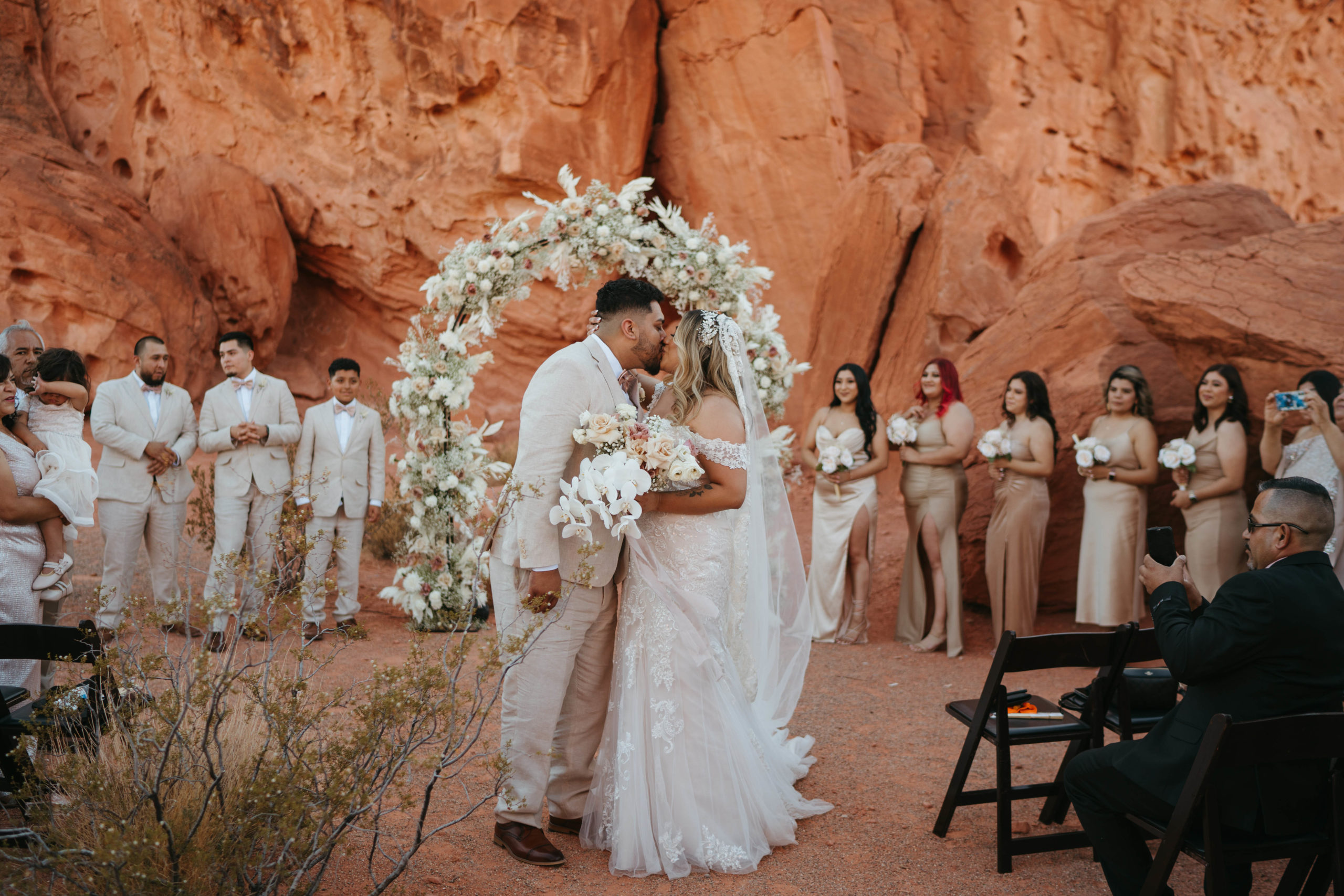 Modern Monochromatic Desert Micro-Wedding. Bride and groom stop in the middle of the aisle to kiss
