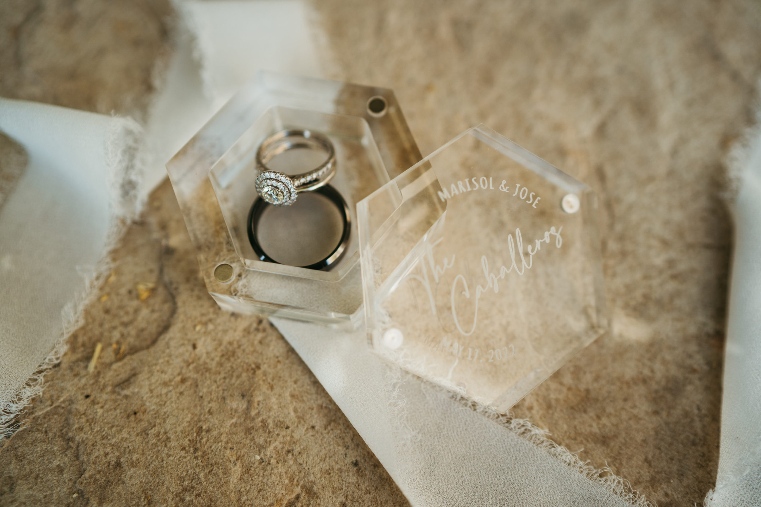 Modern Monochromatic Desert Micro-Wedding. Detail shot of the bride and grooms rings in a custom engraved clear glass ring box.