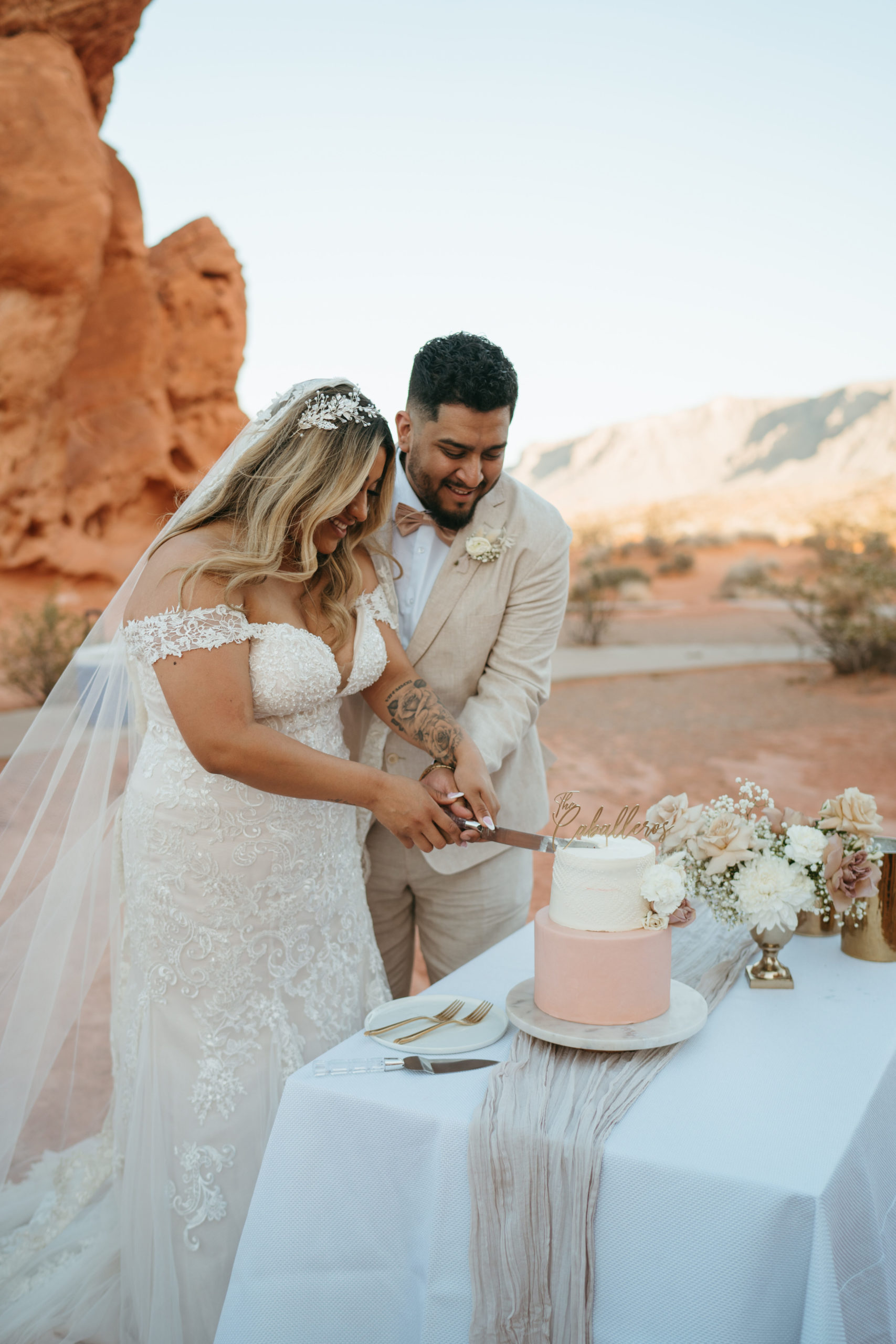 Modern Monochromatic Desert Micro-Wedding. Bride and groom cut the two tier cake at the cake table 