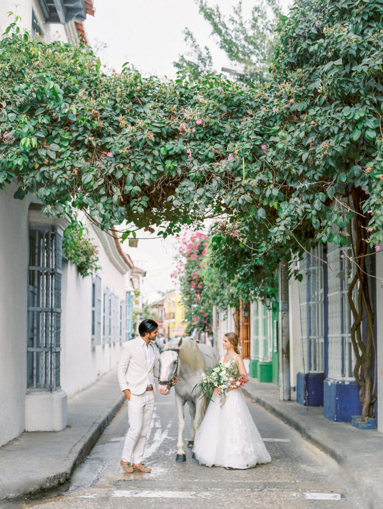 Bride and groom walk with a horse in the colorful streets of Cartagena Colombia
