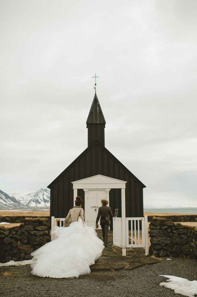Bride and groom walking into the black little chapel in a small town in Iceland