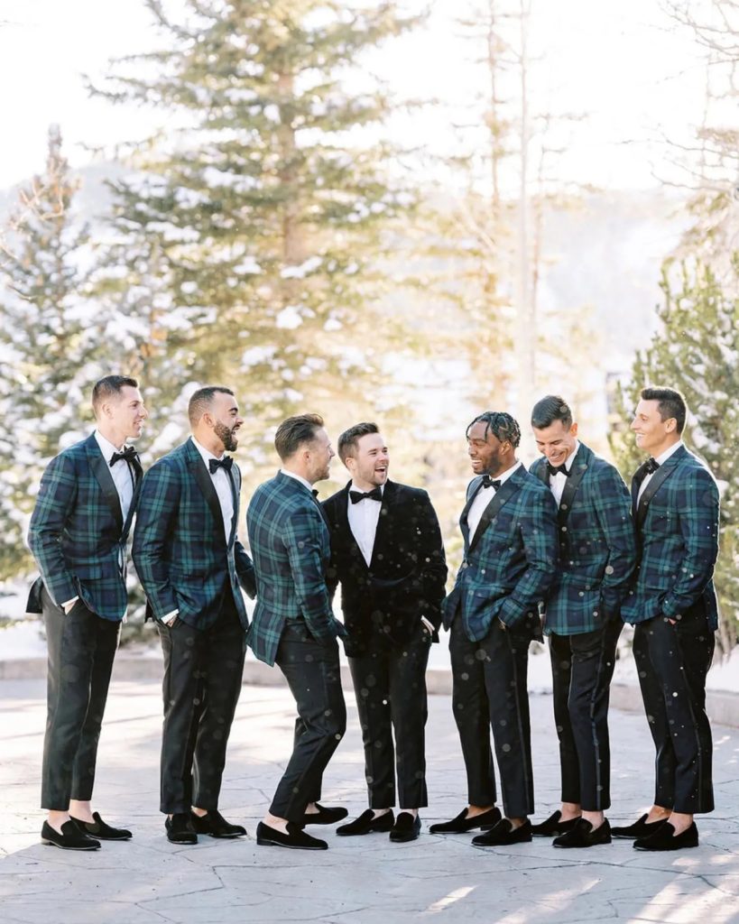 Groomsmen in blue and green plaid suits laughing in the snow 