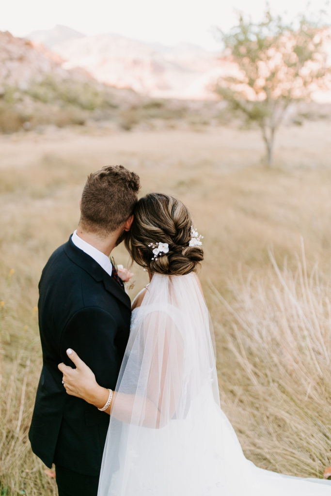 Bride with low bun and floral hair piece with Groom looking off into the distance. 