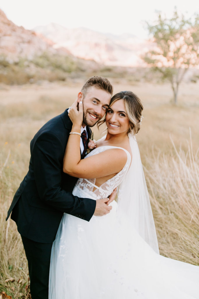 Bride and groom smiling in field 