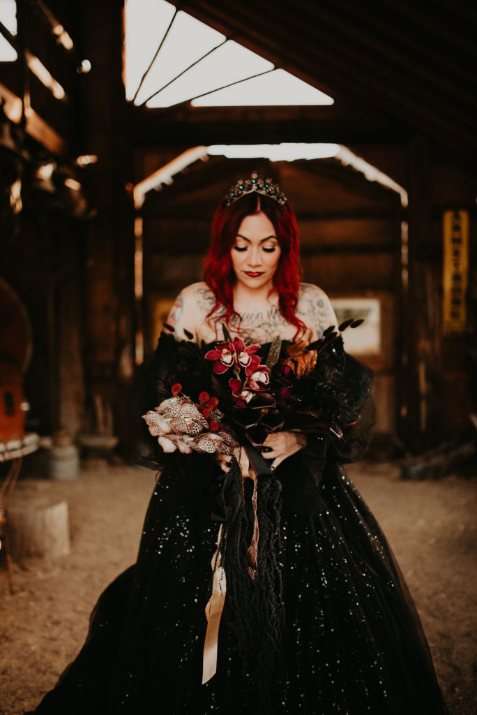 Bride with red hair wearing crown holding black and red moody bouquet for Halloween Themed elopement 
