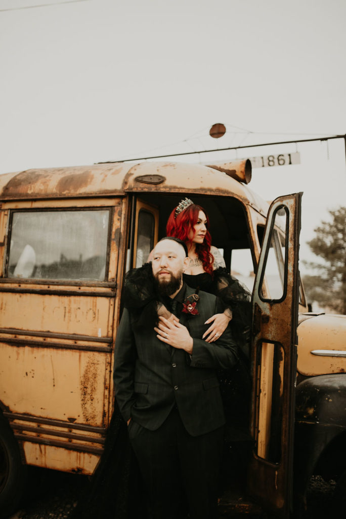 Newlyweds standing in entrance of old school bus for Halloween Elopement at Nelson's Ghost Town