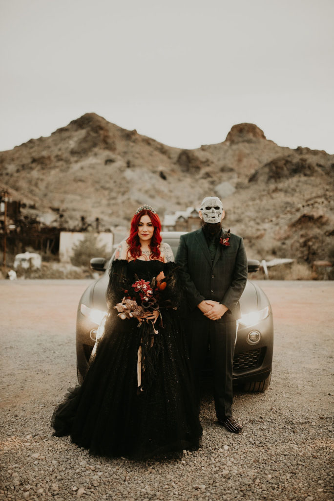 Bride standing next to groom in Halloween Mask for Halloween themed wedding 