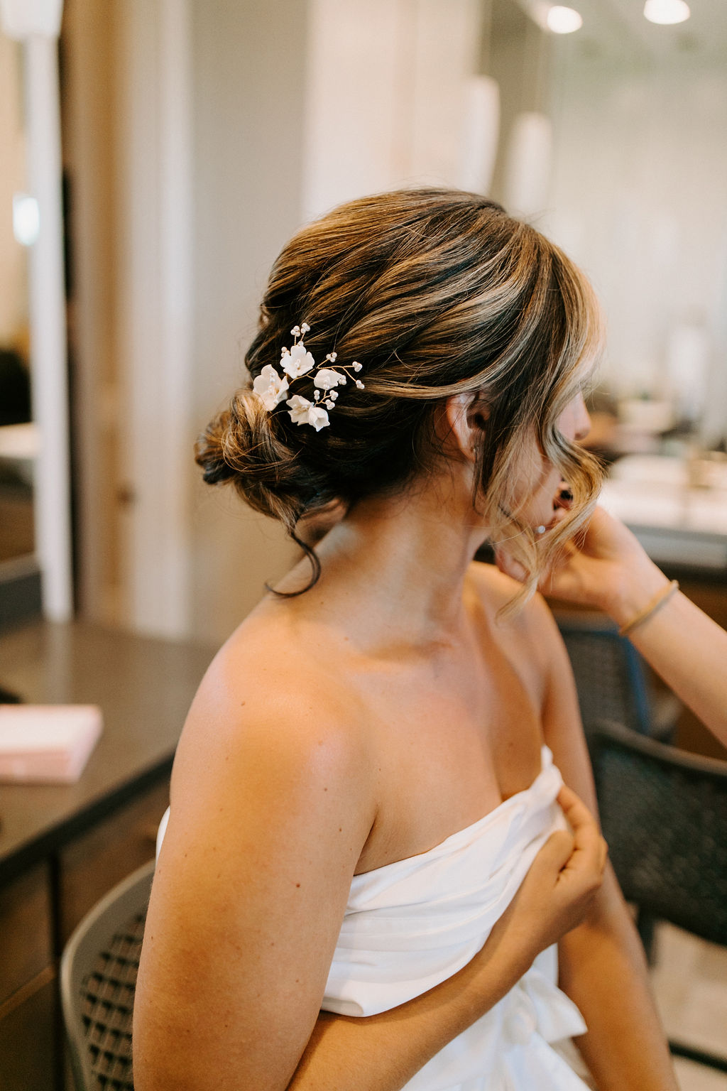 Bride with low bun and curls with white florals in hair. 