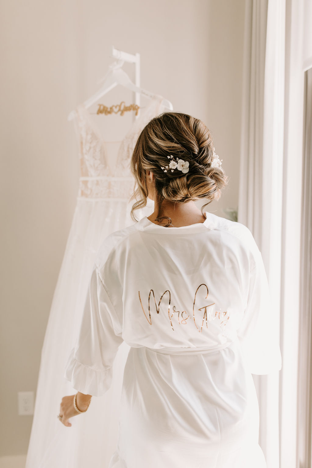 Bride in gold and white custom bridal robe look at bridal dress 