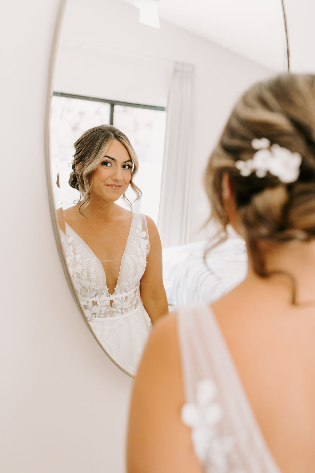 Bride smiling and looking at reflection in mirror 