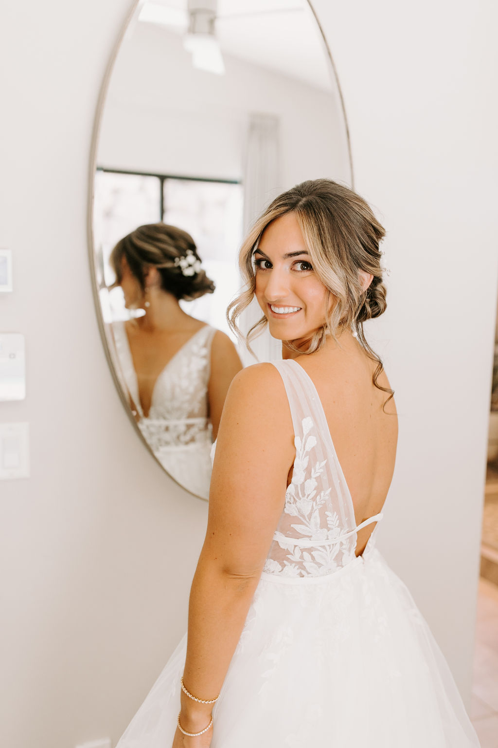 Bride smiling next to mirror while getting ready 