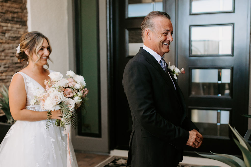 Bride waiting behind father for first look on wedding day 