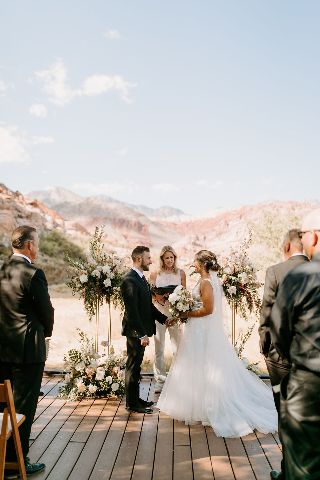 Bride and Groom getting Married with Harlow Stands and Floral and Calico Basin Mountains for Romantic Desert & Backyard Micro-Wedding 