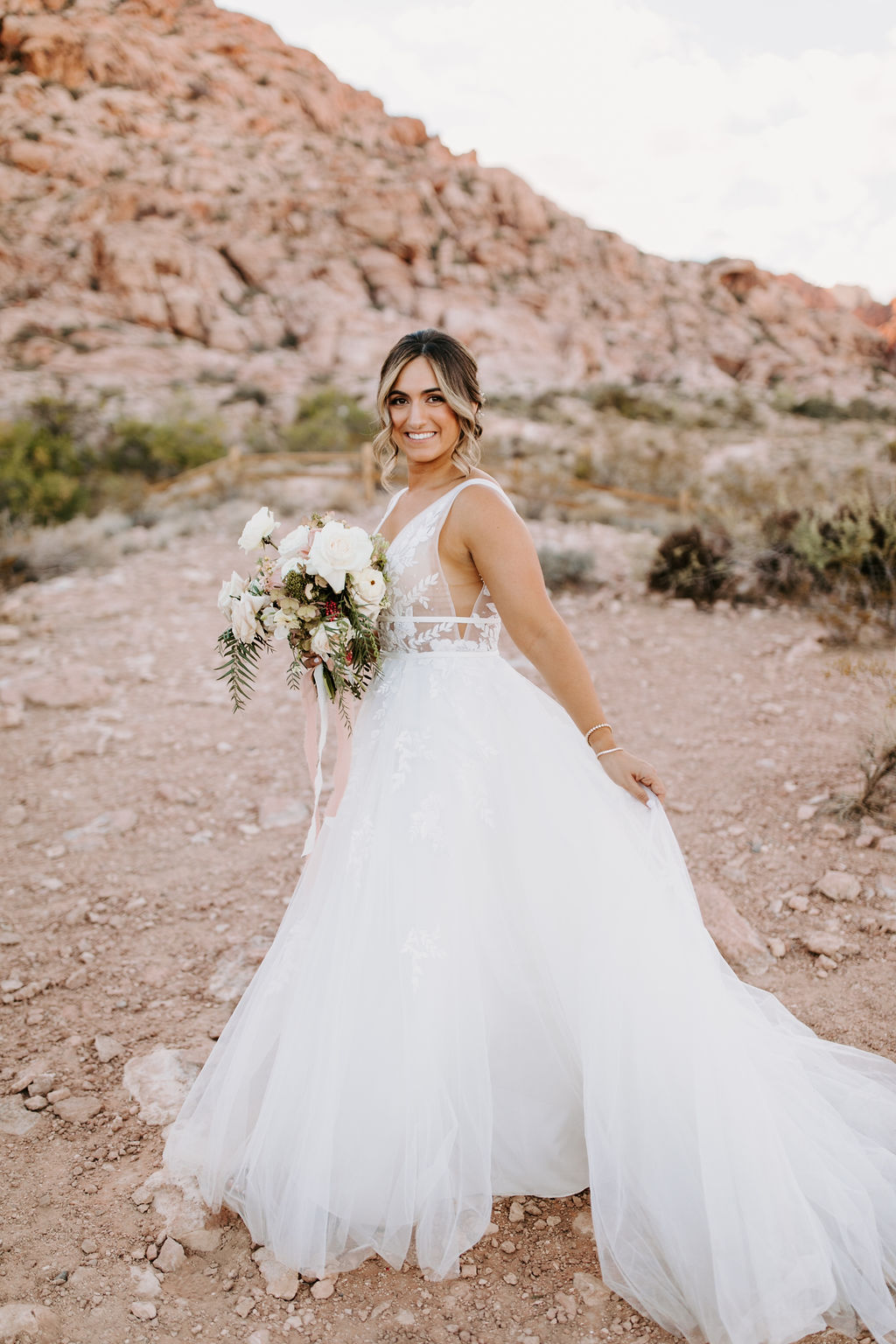 Bride walking in Red Rock Canyon holding her dress 