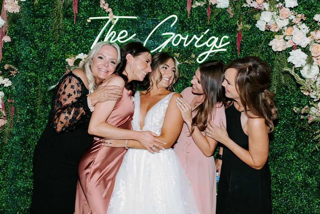 Bride with Guests in front of Neon Sign and Floral backdrop for Romantic Desert & Backyard Micro-Wedding