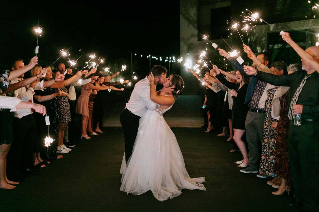 Bride and groom doing grand exit with sparklers in backyard reception 