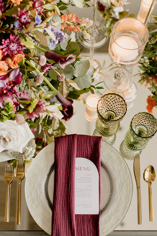 The Color of 2023 Viva Magenta! Magenta inspired tabescape. With a silver charged topped with a magenta cotton napkin and a light color menu card with gold silverware and colored wine glasses. 
