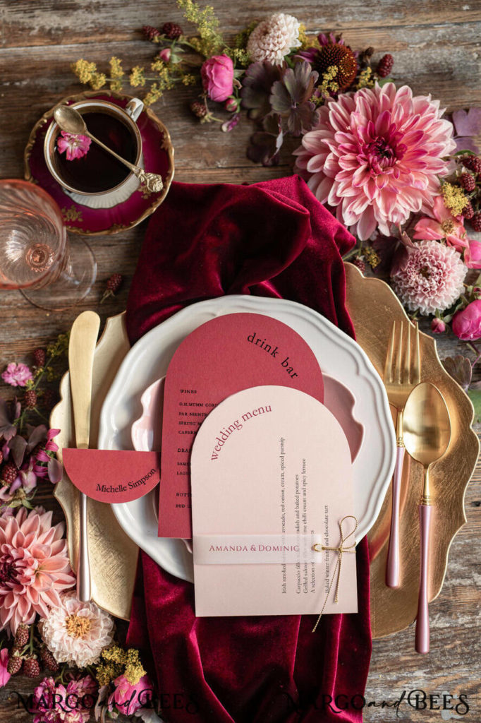 The Color of 2023 Viva Magenta! Magenta inspired tablescape. Using a magenta velvet napkin placed on top of a gold charger with white plating and a light pink salad plate. Hues of magenta used for name and menu card with gold silverware. 