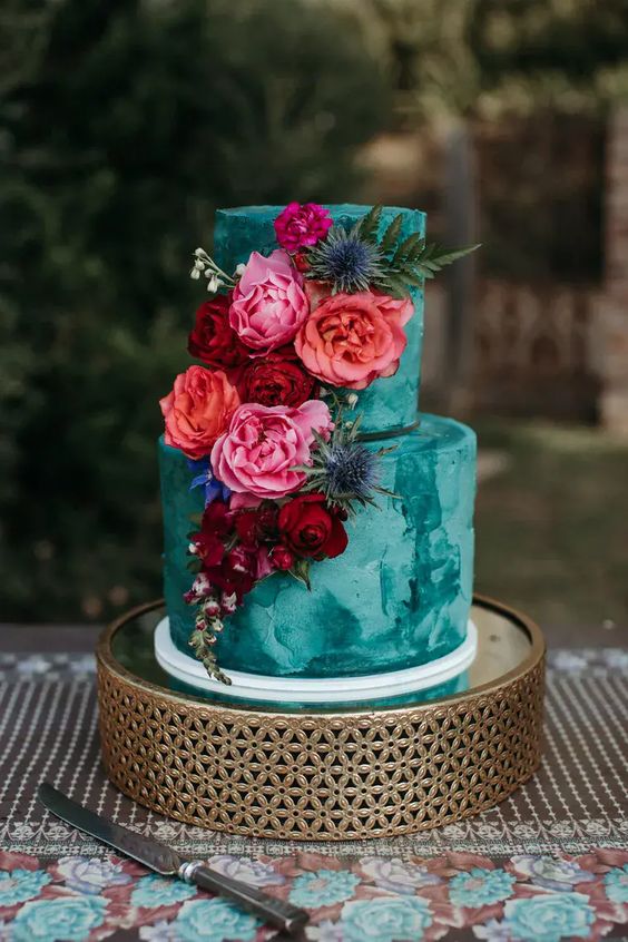 Two tier emerald wedding cake with magenta and complimentary colors placed cascading down.