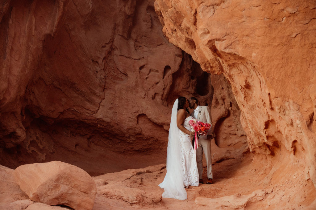 Bold & Colorful in the Vegas Desert. Newlyweds standing in an opening in between the big rocks of valley of fire kissing 