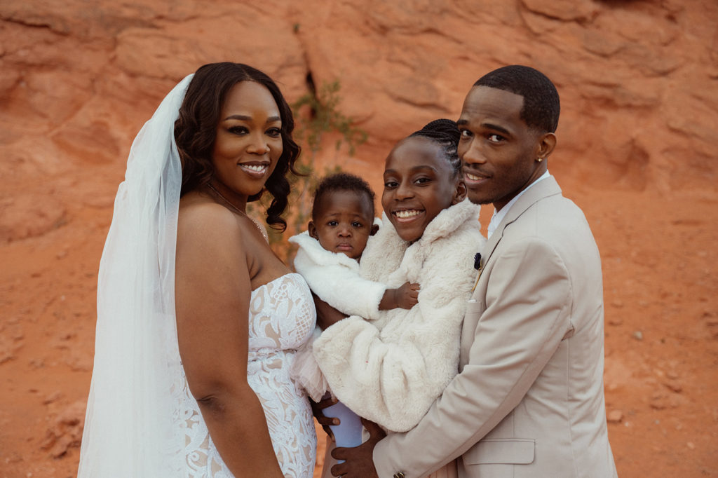 Bride and groom pose for a family photo with their kids at the altar 