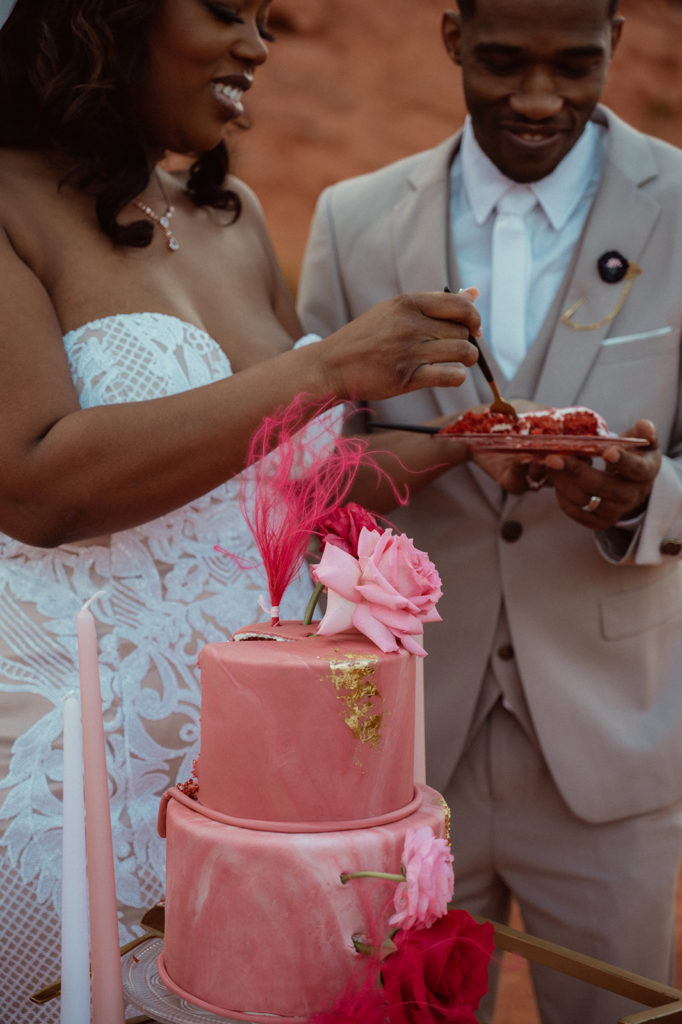 Bold & Colorful in the Vegas Desert. Newlyweds feed each other a bite of the two tier magenta red velvet wedding cake 